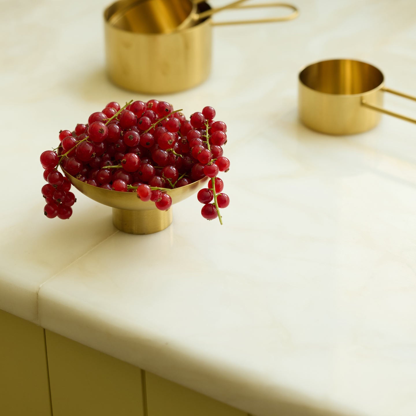 Brass bowl on counter with currants and measuring cups in background.
