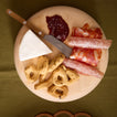 Teak butter spreader on charcuterie board on olive table runner.
