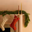 Mantle with wood garland, taper candles, and gingham stockings.
