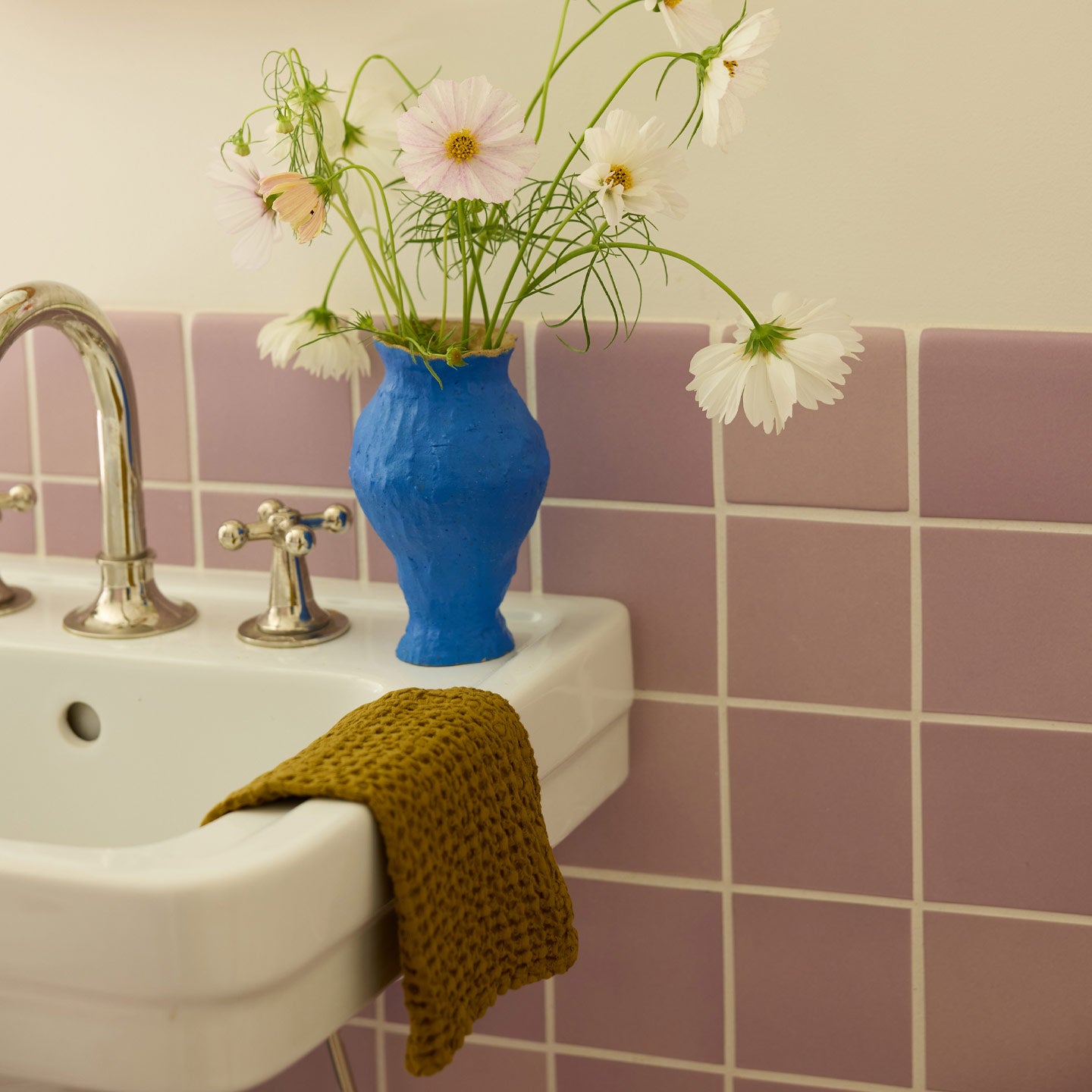 Bathroom sink with bronze washcloth and  blue vase with flowers