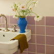 Bathroom sink with bronze washcloth and  blue vase with flowers