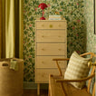 Bedroom with wood dresser and red lamp, chair with gingham pillow, and laundry basket