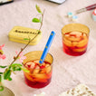 Essential Glass in Amber with iced tea and blue Sabre spoon on table. 