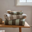 Stack of striped towels on a wooden table with a brush