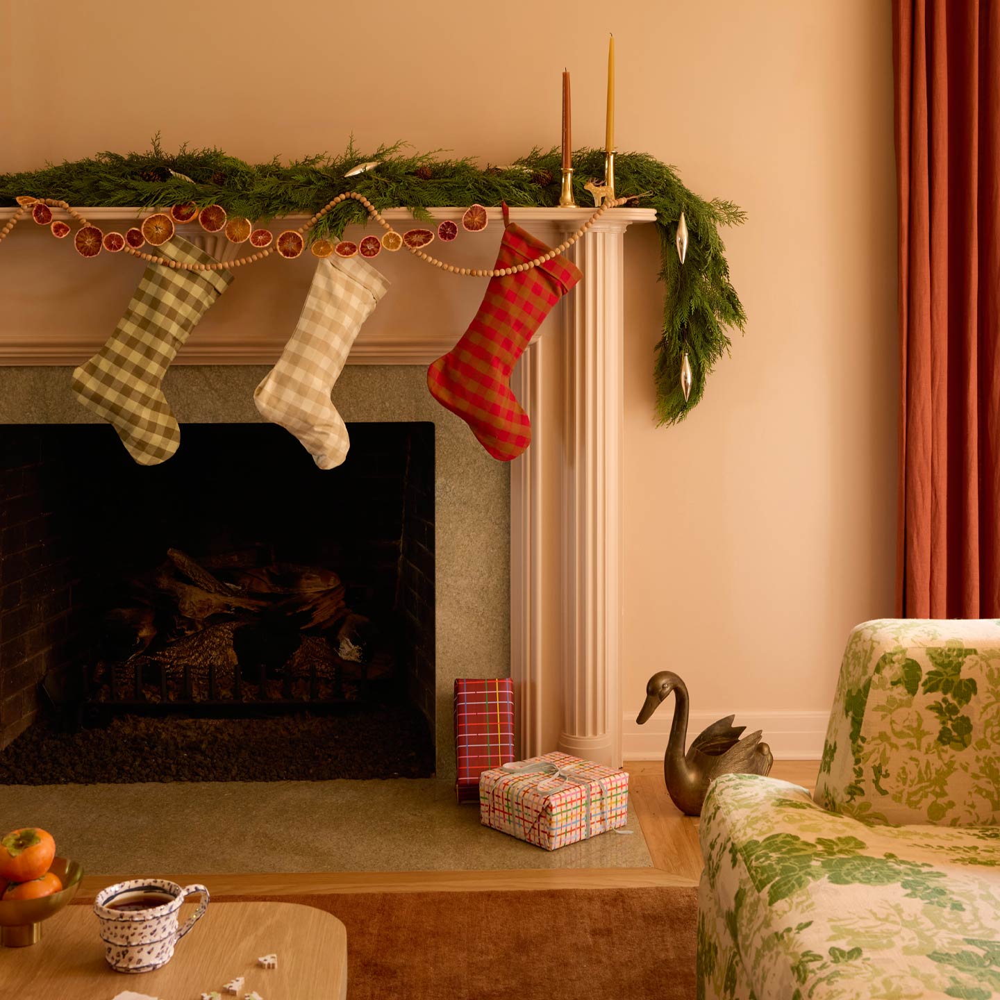 Room with mantle and gifts, stockings, garlands, and taper candles.