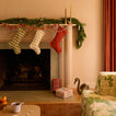 Room with mantle and gifts, stockings, garlands, and taper candles.