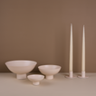 A trio of footed bowls and pair of candle holders, all in Ivory, with ivory taper candles.