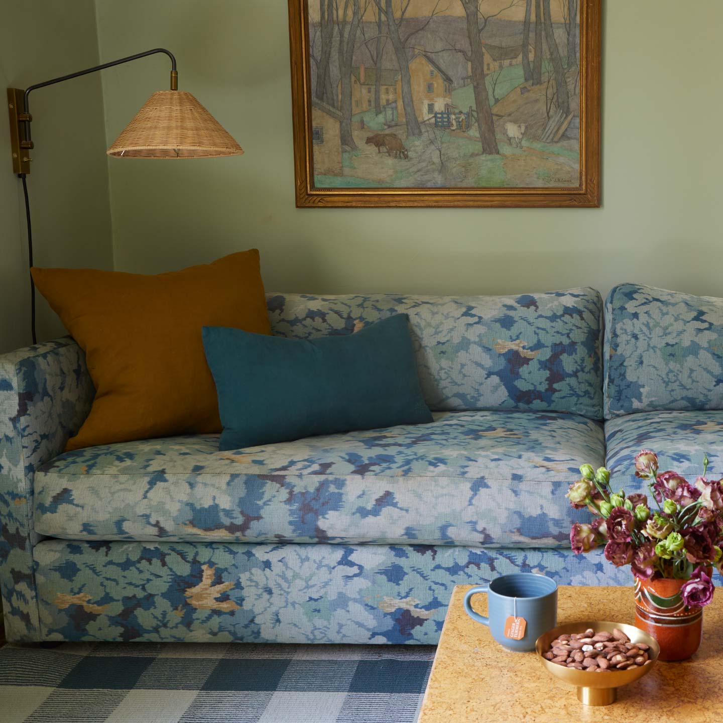 Living room with a floral-patterned sofa, decorative pillows, and a painting on the wall.