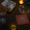Cocktail glasses on a dark surface with a candle and dessert