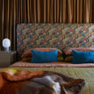 Bed with patterned headboard and colorful bedding in a bedroom setting.