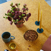 Essential metal candle holder on table with vase, florals and mug