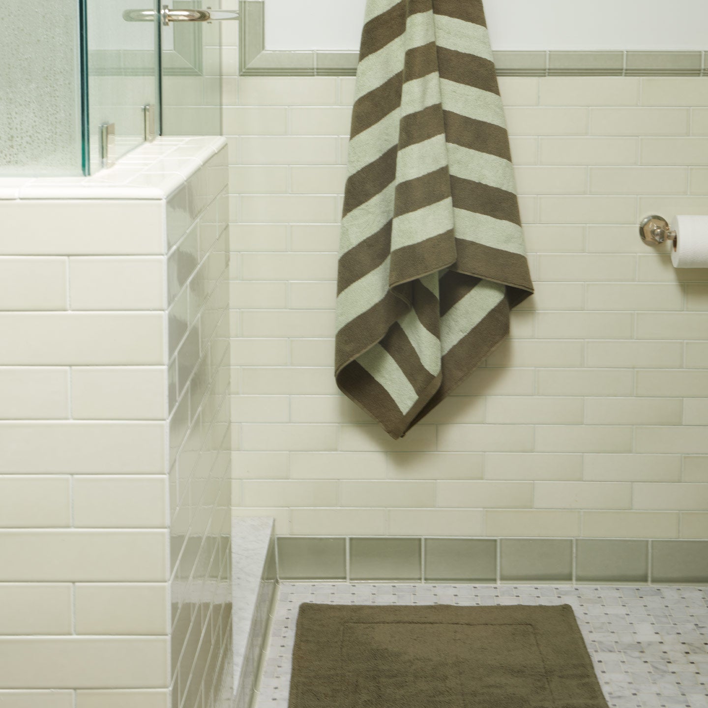 Striped towel hanging on a rack in a bathroom with tiled walls and floor.