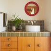 Bathroom countertop with vases and towel hanging on wall.