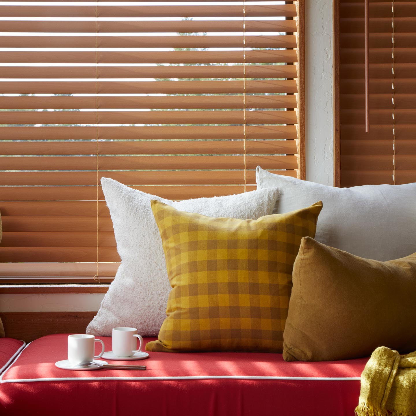 Window seat with pillows and espresso mugs.