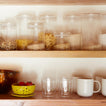 Shelf with glassware, essential glass storage, tomatoes in berry bowl, and simple porcelain mugs.