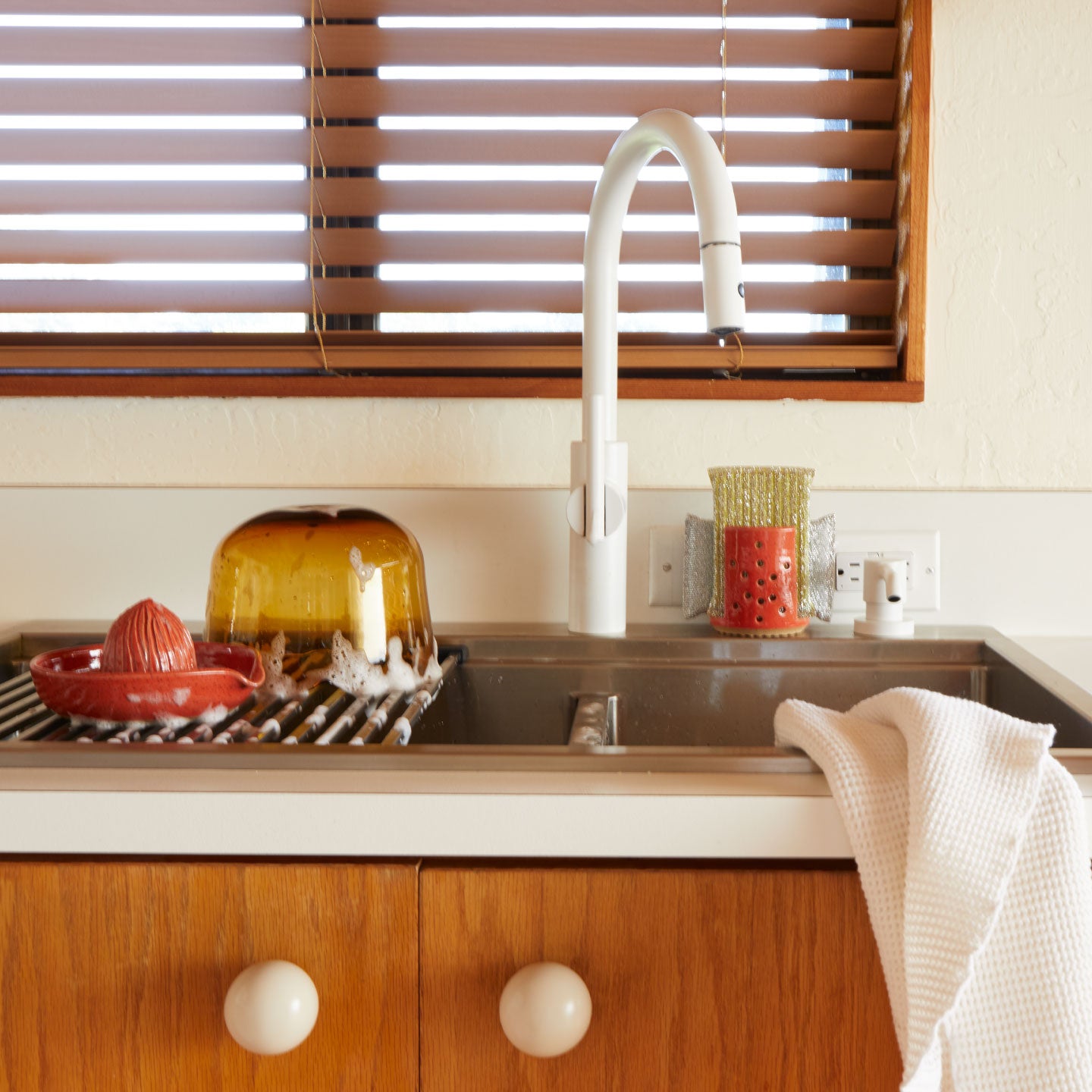 Kitchen sink area with wooden cabinets and a window above
