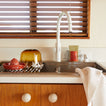 Kitchen sink area with wooden cabinets and a window above