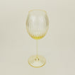 Three-quarter angle of ribbed amber wine glass.