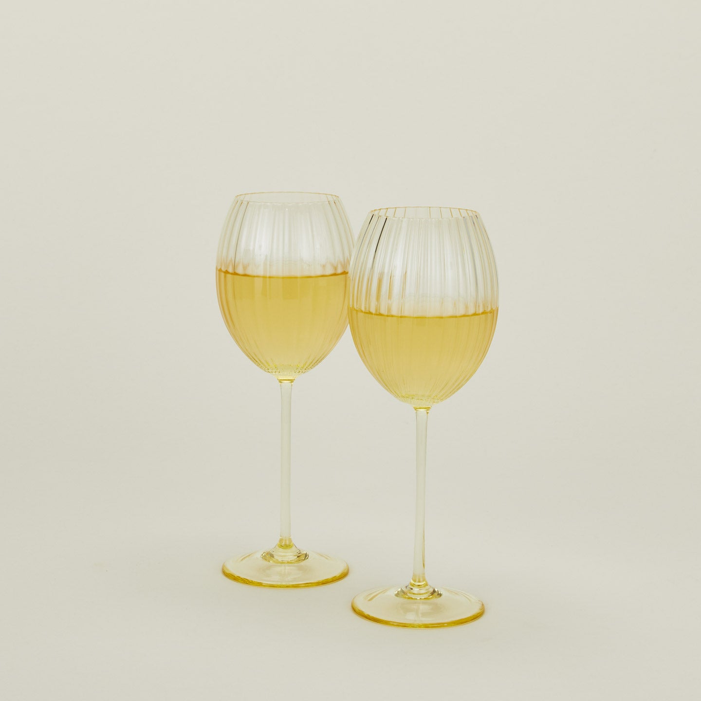 Set of two ribbed amber wine glasses with white wine.