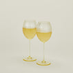 Set of two ribbed amber wine glasses with white wine.