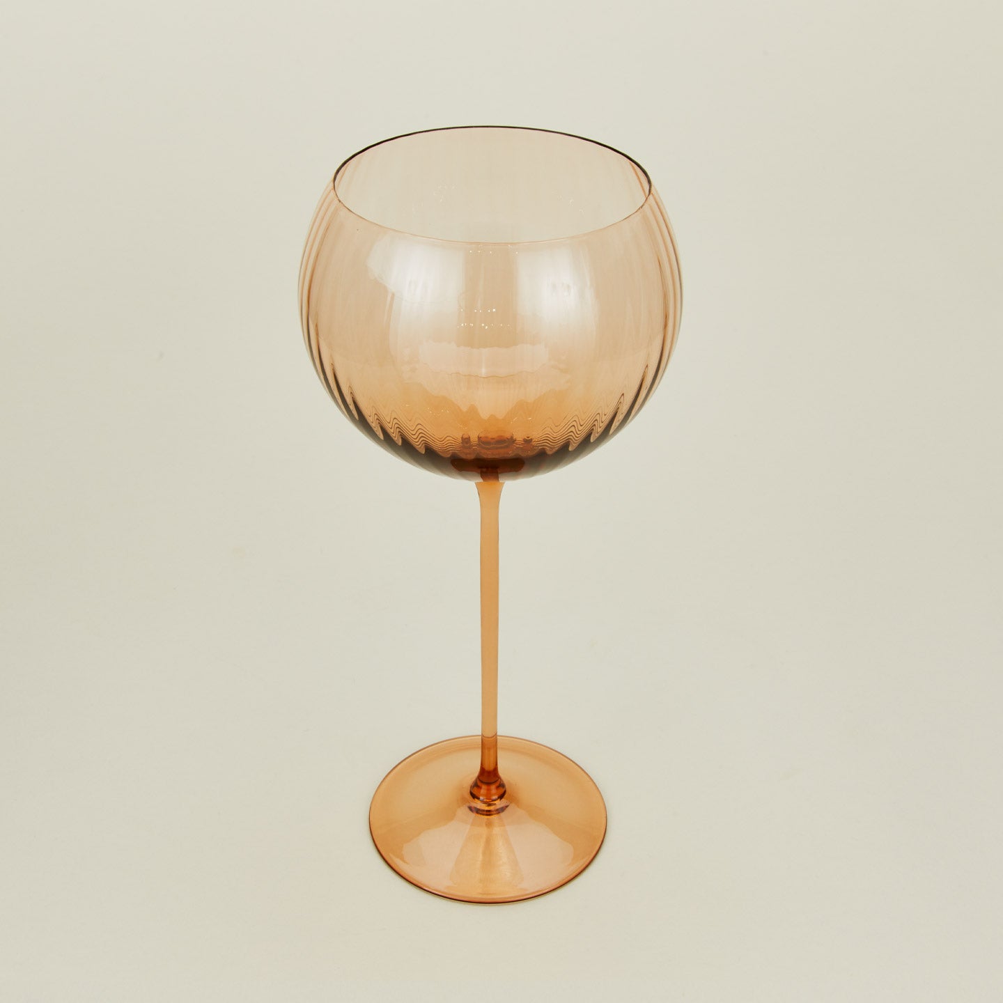 Three-quarter angle of ribbed brown wine glass.