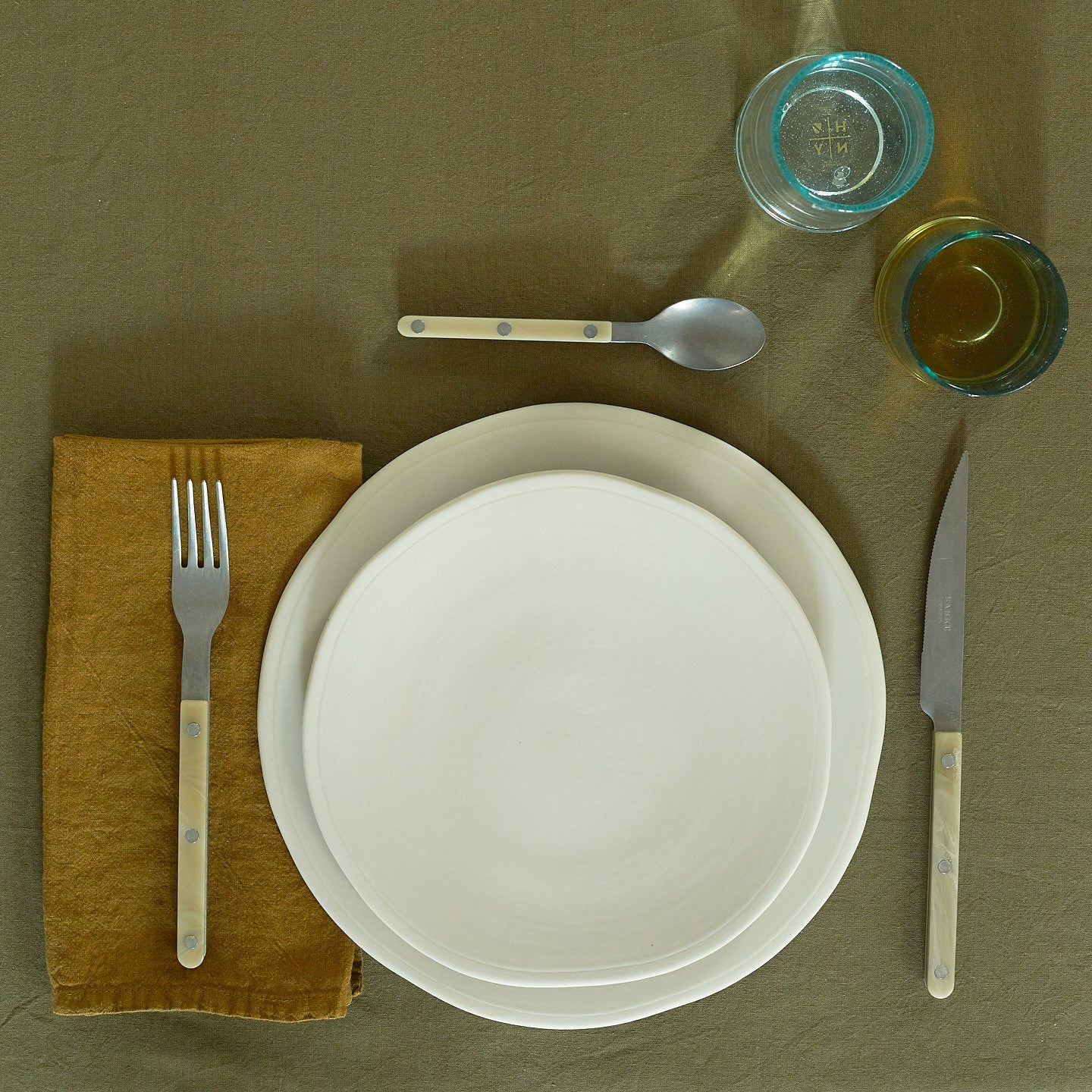 Placesetting with Atelier Salad Plate on green tablecloth.