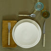 Placesetting with Atelier Salad Plate on green tablecloth.