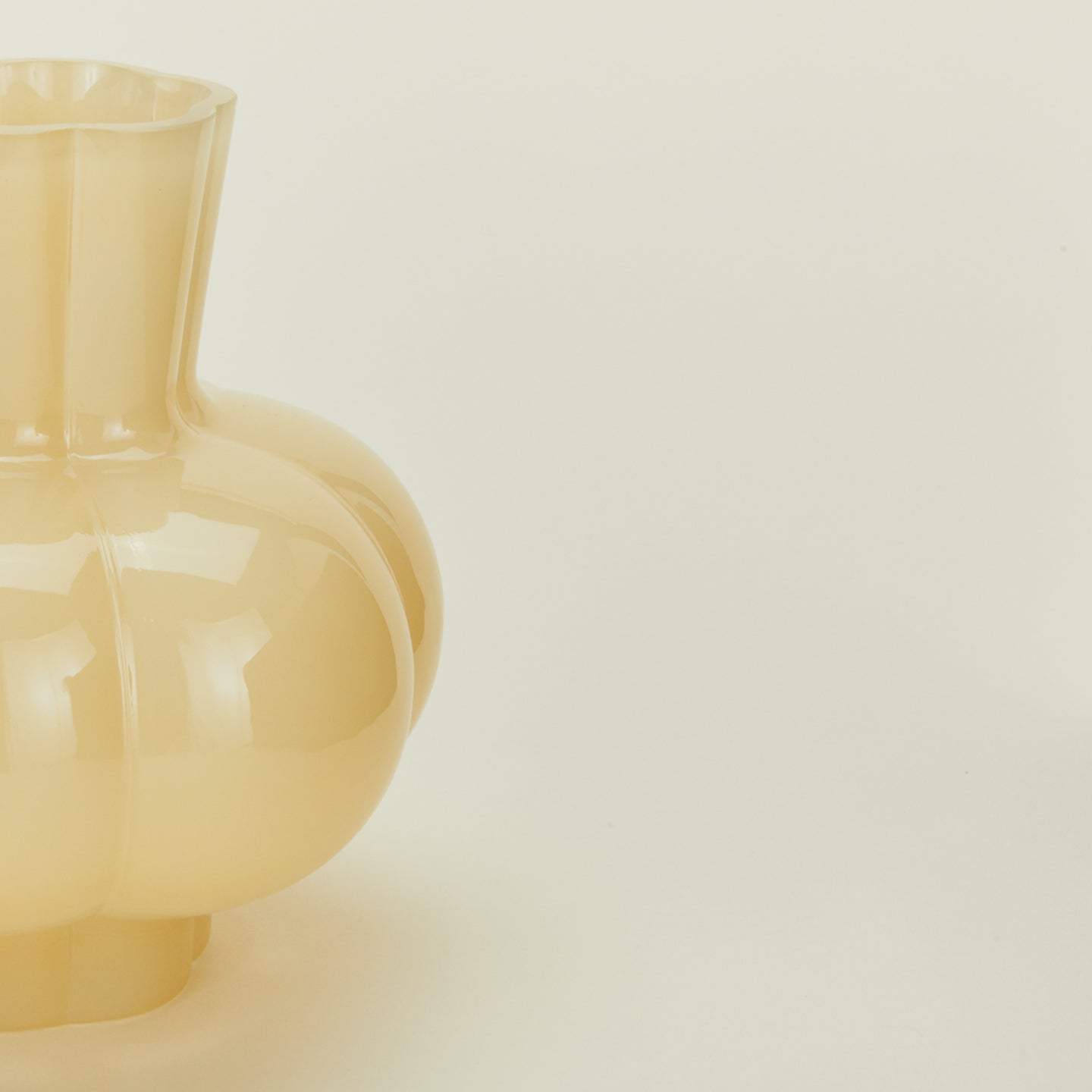 Close up view of opaque yellow glass pleated vase