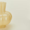Close up view of opaque yellow glass pleated vase