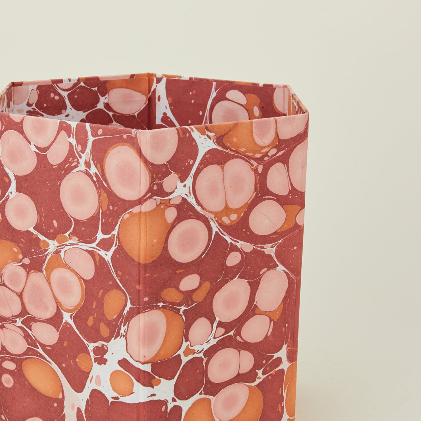 Detail of marbled hexagon wastebasket in warm tones.