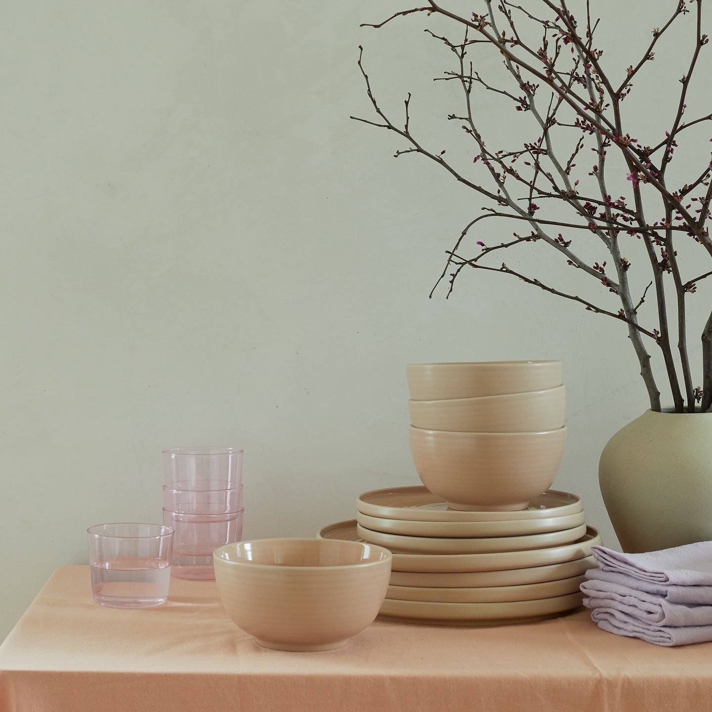 Tabletop with stacked Essential Dinnerware and Essential Glassware in Blush.
