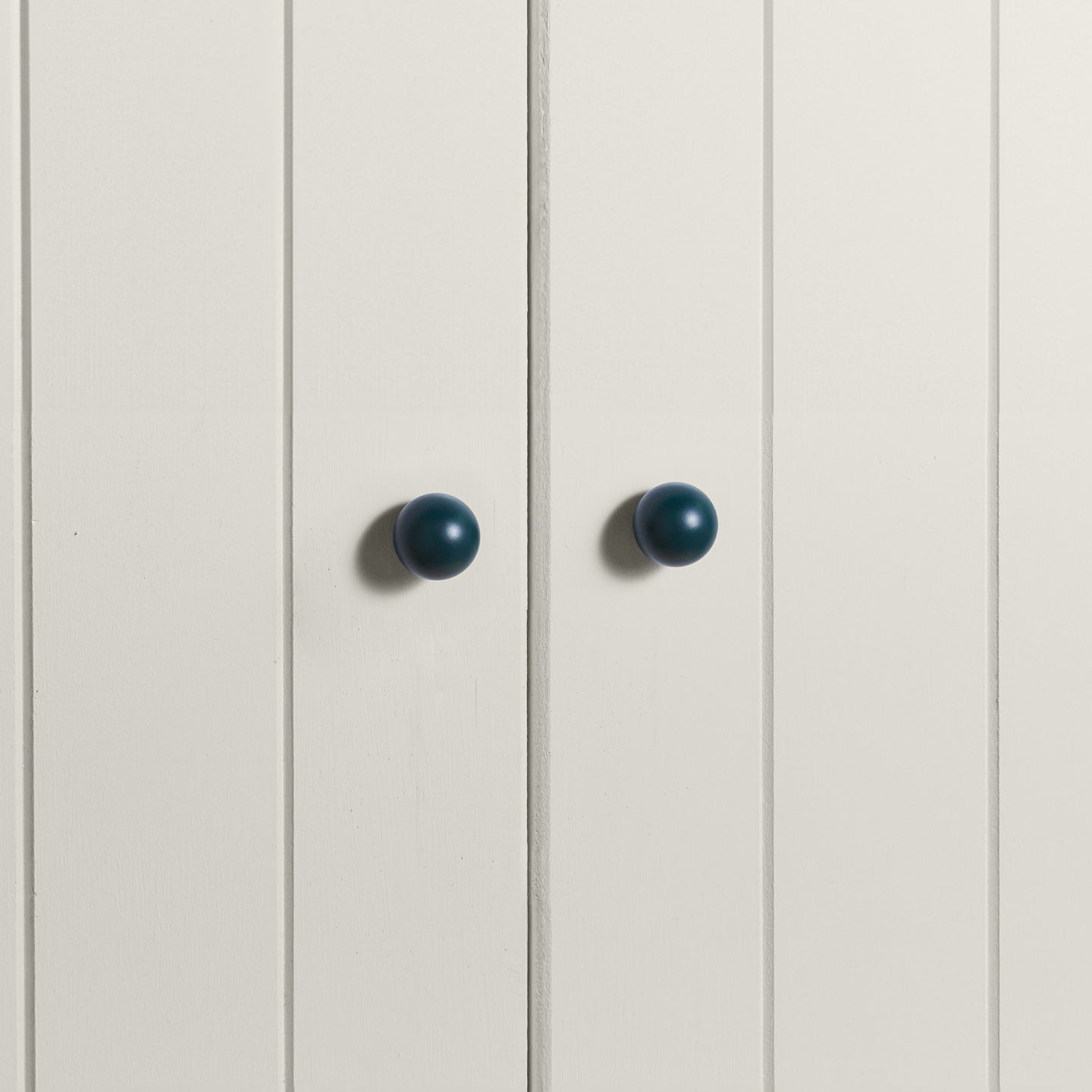 Small peacock essential sphere knobs on white doors