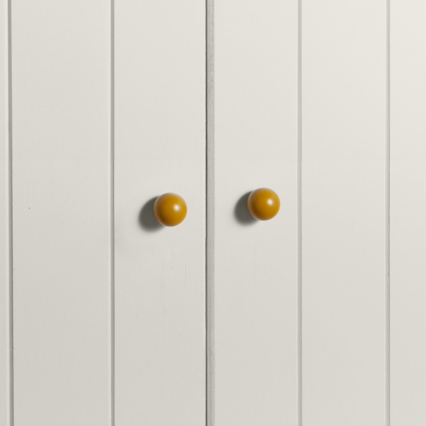 Small mustard essential sphere knobs on white doors
