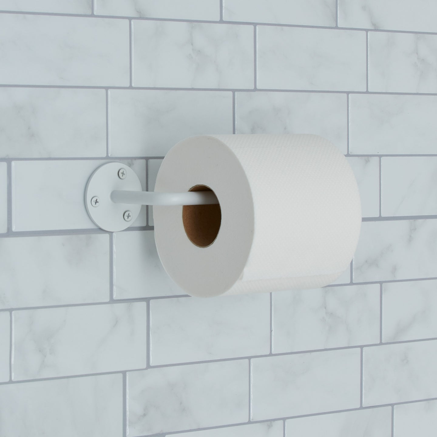 Essential toilet paper holder in white on tile background.