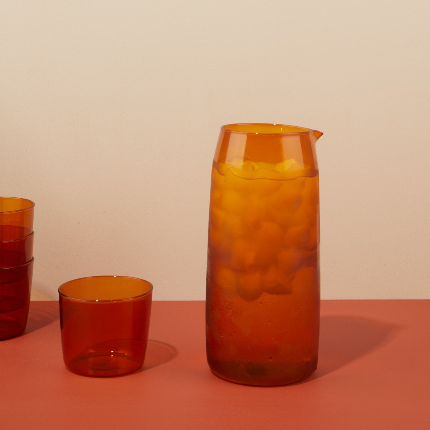 Essential Pitcher in Terracotta with ice and water on surface with Essential Glassware.
