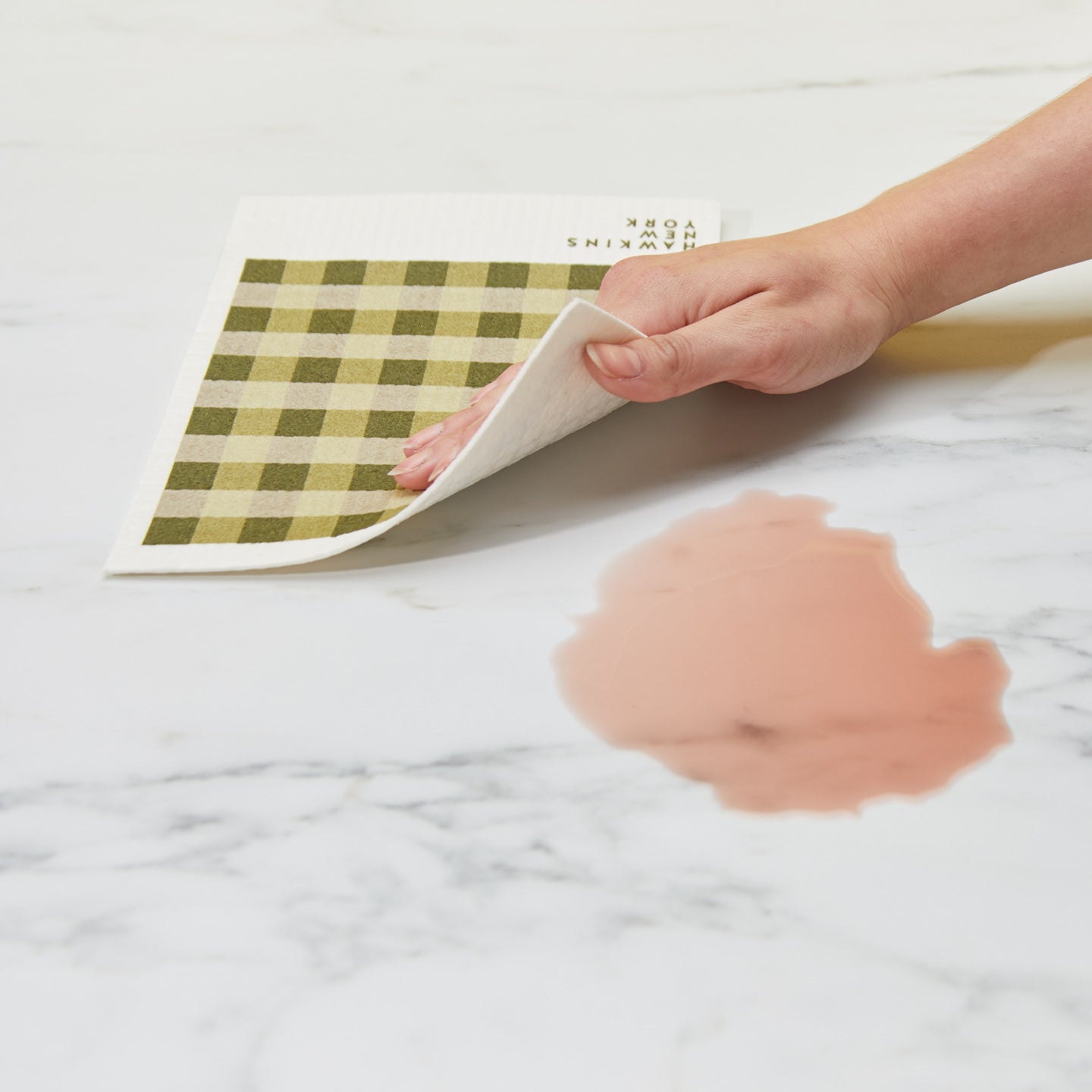 Hand cleaning spill on surface with Essential Swedish Dishcloth in Olive.