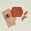 8x8 bakeware in terracotta with sweet potatoes dishtowel and brass measuring cups