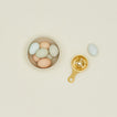 Brass egg separator on a beige background with a bowl of colorful eggs.
