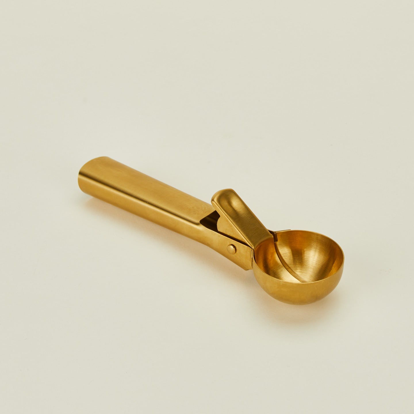 Close up of brass ice cream scoop on a beige background
