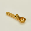 Close up of brass ice cream scoop on a beige background