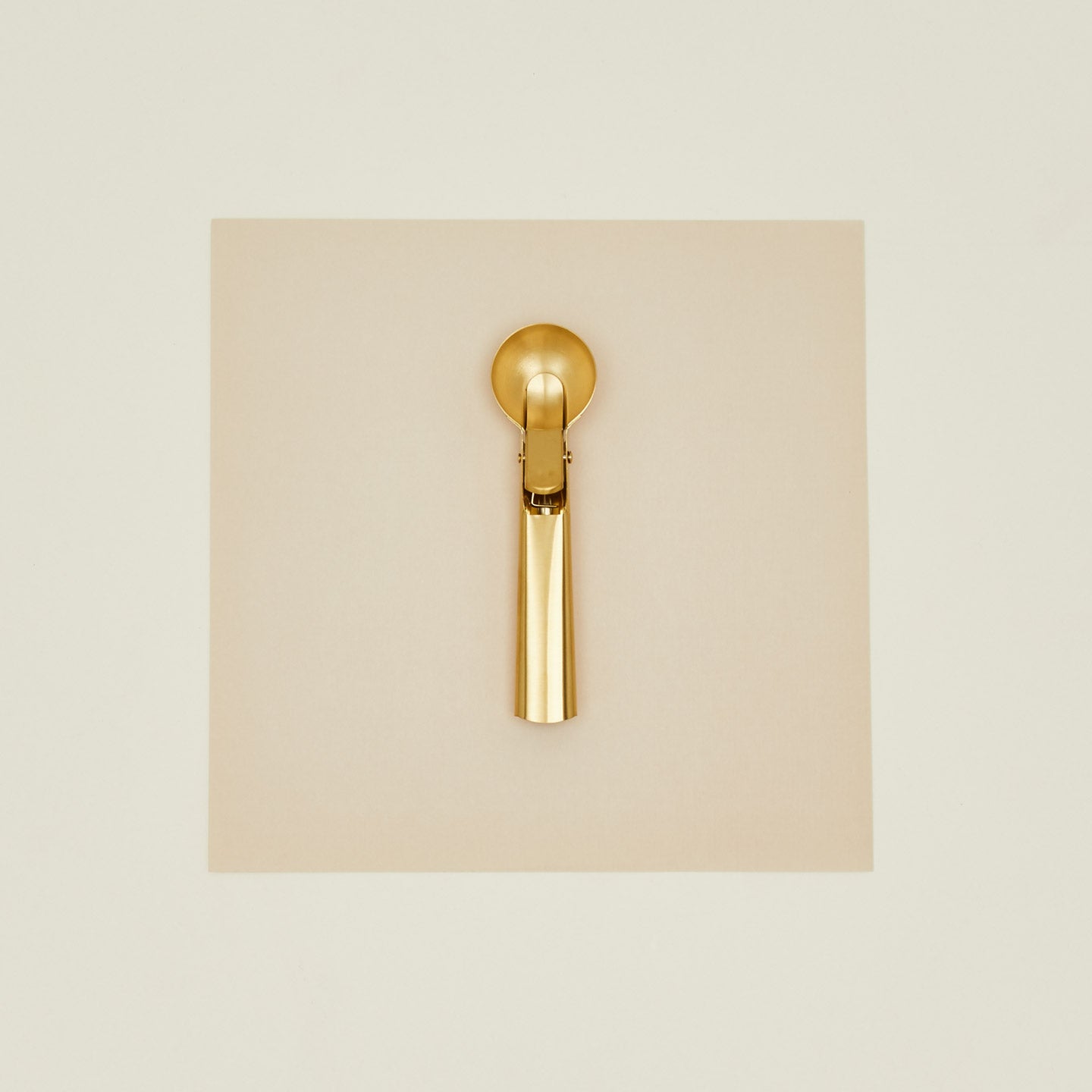 Brass ice cream scoop on a beige background
