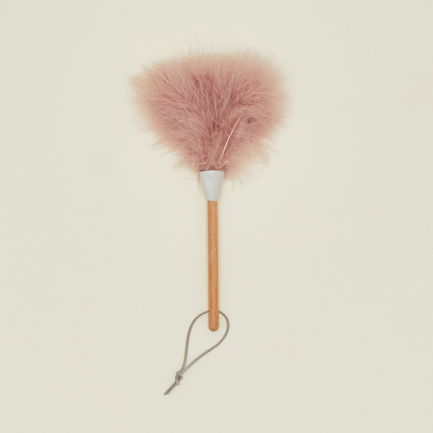 Pink feather duster with wooden handle on a beige background
