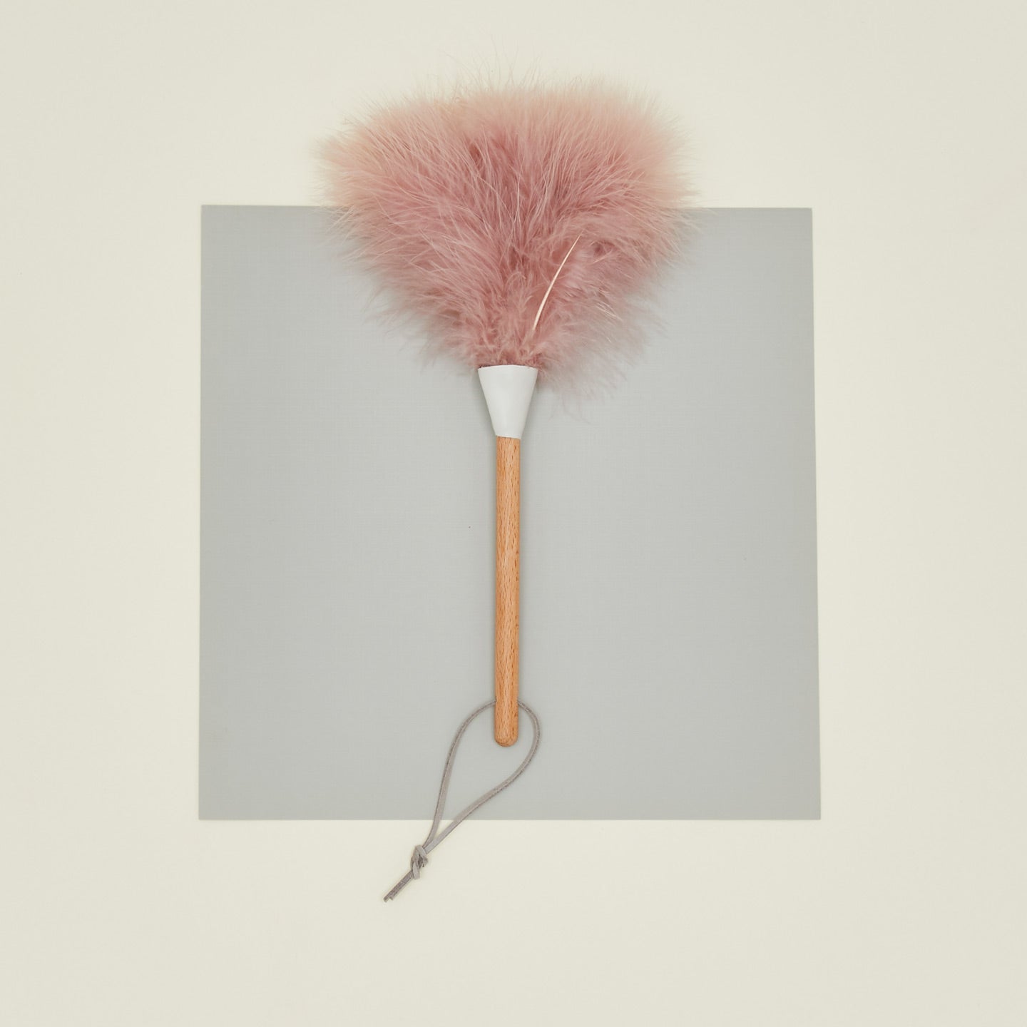 Pink feather duster with wooden handle on a gray background