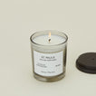 A close up of a lit wax candle with the scent St. Pauls.