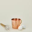 Copper liquid measuring cup with whisk and eggs