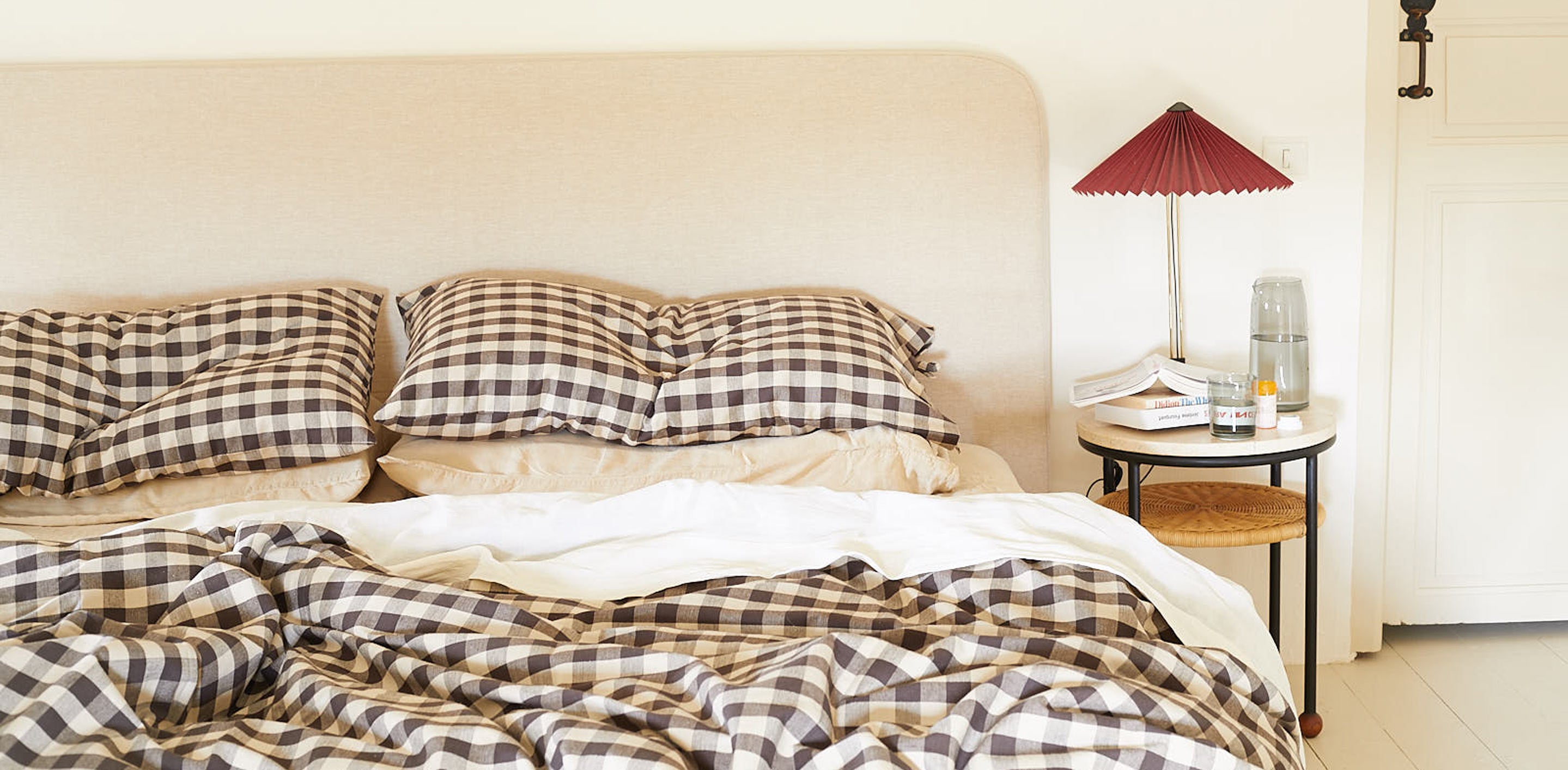 Bedroom with checkered bedding and a lamp on a nightstand.