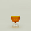 Drinking glass with clear stem and amber cup, filled with ice water.