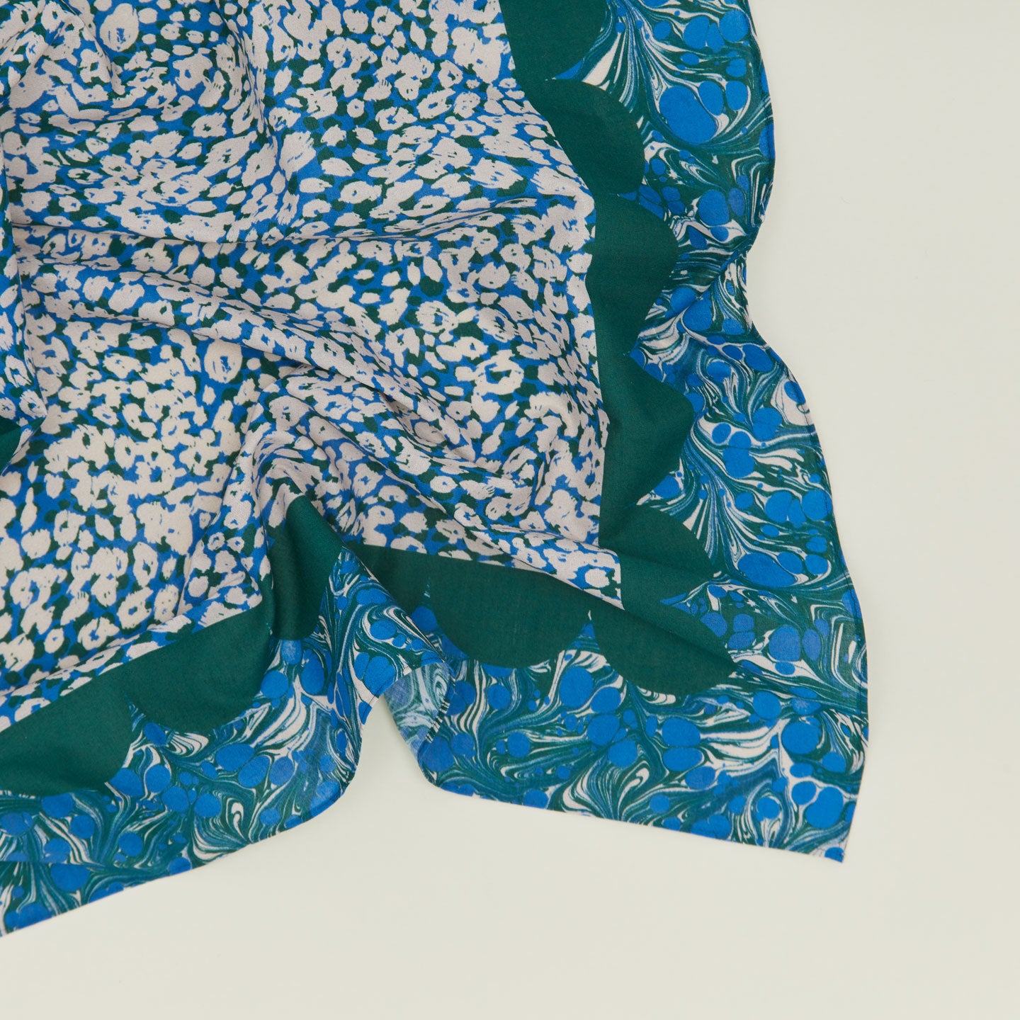 A close up of a mixed floral napkin with an evergreen pattern.