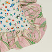 A close up of a ruffled floral cushion with a peony pattern.