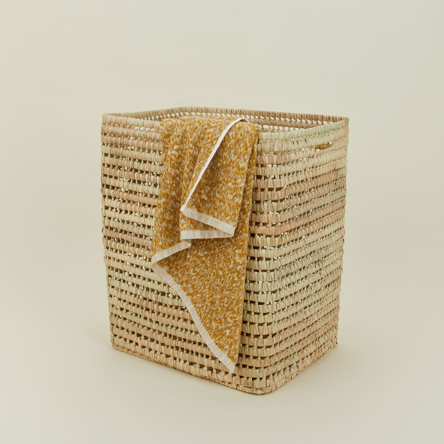 Open weave hamper with mustard space dye towel draped over the side